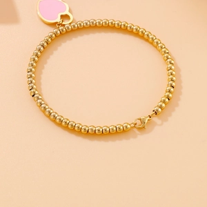 Detail view of 18k gold plated beaded bracelet featuring a pink heart pendant with clasp