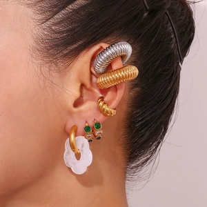 Close-up of assorted gold and silver ear cuffs with floral charms on a woman's ear