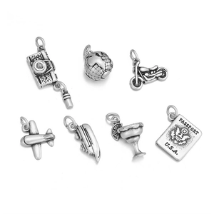 Macro detail of seven silver travel-themed charms including passport, camera and plane