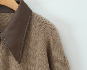 Detailed close-up of brown knit cardigan with faux leather contrast collar detail