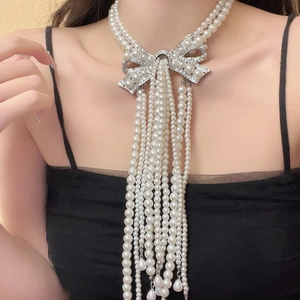 Detailed close-up of multi-layer pearl necklace with a crystal bow and long tassels