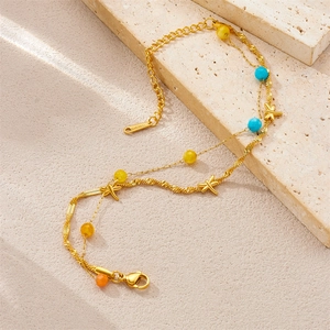 Macro shot of double-layer gold stainless steel bracelet with colored beads and charms