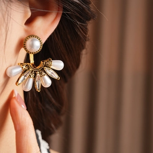 Detailed view of vintage fan-shaped earrings with pearls and crystals on a female model