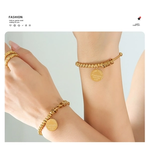 Detail of gold beaded stretch bracelets and textured rings on model wrist