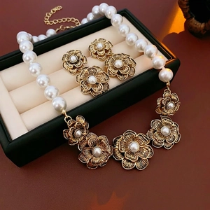 Vintage jewelry set with pearl necklace and golden flower earrings in luxury jewelry box