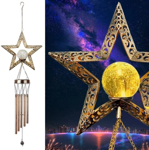 Detail of golden metal star solar wind chime with glowing glass ball and five hanging tubes