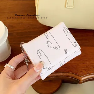 Pink trifold wallet with cute rabbit print and bow charm on a cozy cafe background