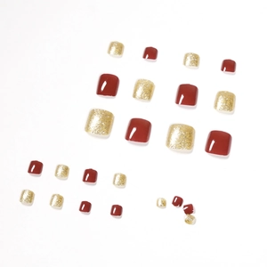 Unghie finte per piedi rosso scuro e glitter oro su sfondo bianco pulito