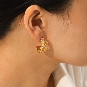 Close-up of 18K gold-plated twisted hoop earrings with sparkling zircon stones on a model