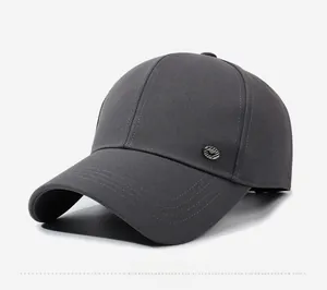 Close-up of dark grey twill baseball cap with detailed round metal emblem and stitching