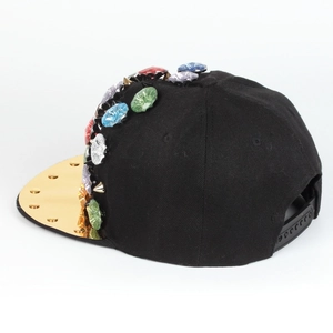 Detail einer Punk-Snapback-Cap mit bunten Strasssteinen, Metallstacheln und Goldvisier