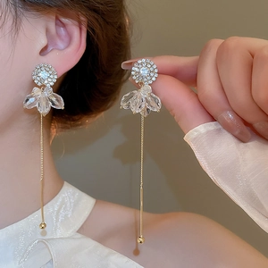 Detail of elegant gold drop earrings featuring rhinestones and long tassel spheres on model