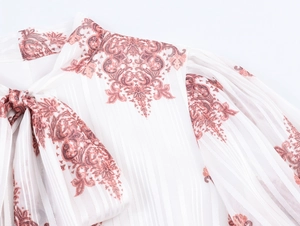 Dettaglio di abito bohémien bianco con stampa paisley, scollo con lacci e trama a righe