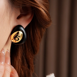 Close-up of a vintage black water-drop earring with gold plating on ear model