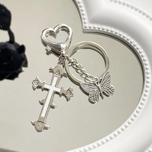 Gothic silver butterfly cross keychain with heart clasp on a mirror background
