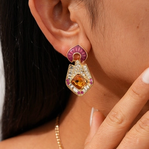Gros plan d'une boucle d'oreille vintage dorée avec pierre ambre et émail violet