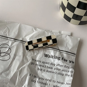 Close-up of black and white checkered rectangle hair clip on a vintage paper background