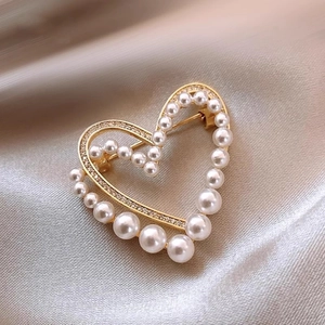Elegant gold heart brooch with pearls and rhinestones on champagne silk background