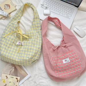 Detail of canvas tote bags with plaid patterns and bow tie closure in a lifestyle setting