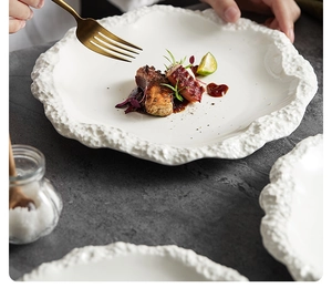 Dettaglio ravvicinato di un piatto in ceramica bianca con bordo a trama rocciosa increspata