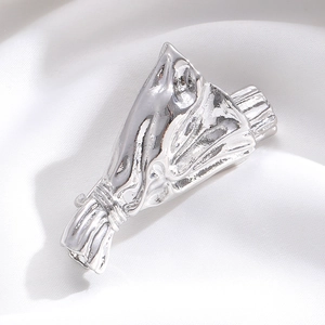 Macro shot of silver bouquet brooch with mirror finish on silk fabric background