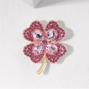 Detailed view of pink crystal four-leaf clover brooch with gold base and purple rhinestones