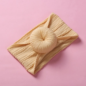 Detail of yellow nylon donut headband with twisted knot design on pink background