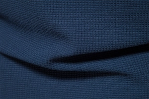 Macro shot of navy blue waffle knit fabric showing premium honeycomb texture and soft drape