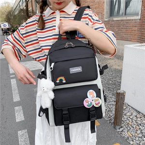 Detail of black and white fashion backpack with cute badges and plush bear pendant