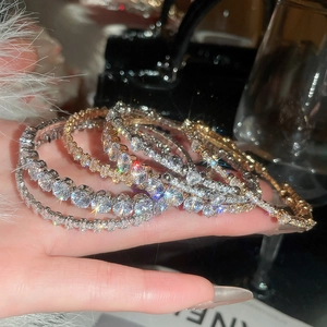 Close-up of luxury sparkling zircon bracelets in gold and silver with hand display
