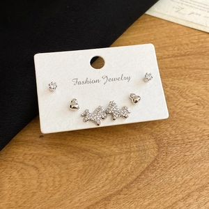 Détail du lot de boucles d'oreilles argentées avec zircons et motifs de chiens sur carte