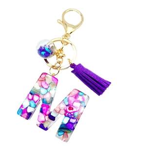 Resin alphabet M keychain with colorful stones, purple tassel, and star charm