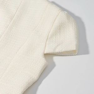 Dettaglio della trama in tweed bianco del top a maniche corte elegante e tessuto