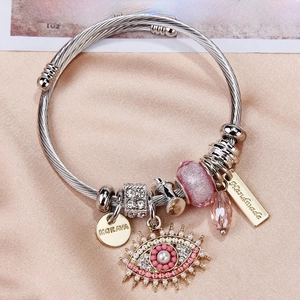 Detail of silver twisted bangle with pink evil eye charm and handmade brand tag