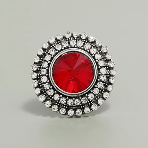 Macro shot of circular vintage ring with a large red center stone and clear crystal halo