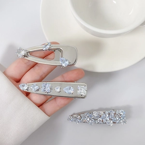 Detail of three silver hair clips with micro-set zircons in water drop and square shapes