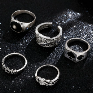 Detail of silver gothic ring set featuring 8-ball, spade, and skull motifs on black background
