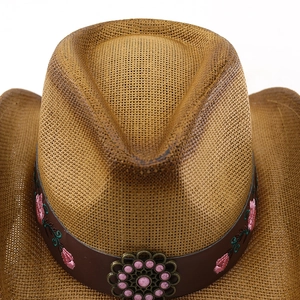 Close-up of brown straw cowboy hat with floral embroidery and vintage metal buckle