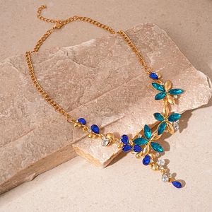 Detail of vintage gold flower pendant with blue and white crystals on stone surface