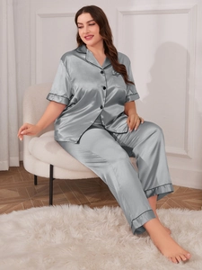 Close-up of silver-gray satin pajama set with black piping and button-down detail