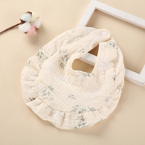 Gros plan d'un bavoir en coton pour bébé avec imprimé floral vert et bords à volants