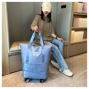 Detail view of the expandable light blue travel bag featuring multi-directional swivel wheels