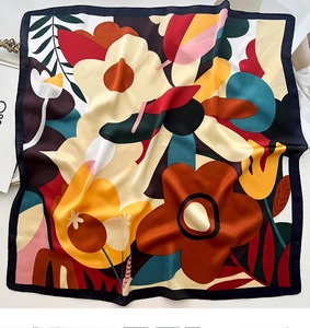 Close-up of square silk scarf showing abstract floral print and smooth satin texture