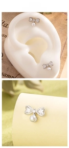 Macro view of silver bow-shaped earring with heart zircon and pearl pendant detail