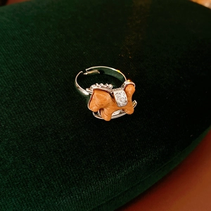 Macro detail of wooden rocking horse ring with zircon saddle on green velvet