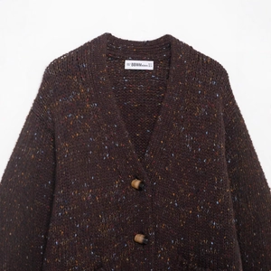Brown V-neck knit cardigan with colorful speckled yarn and amber buttons in flat lay view