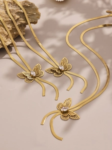 Detailed macro shot of gold snake chains with hollow butterfly pendants and clear zircons