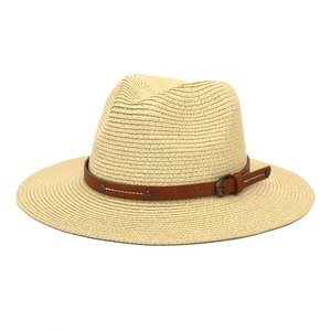 Detailed view of straw Panama hat featuring a brown leather belt with metal studs