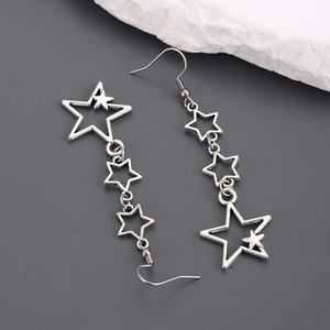 Détail de boucles d'oreilles étoiles évidées argentées sur fond gris avec décor