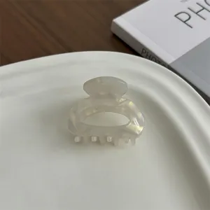 Detailed close-up of a pearlescent cream mini hair claw clip made of acetate resin